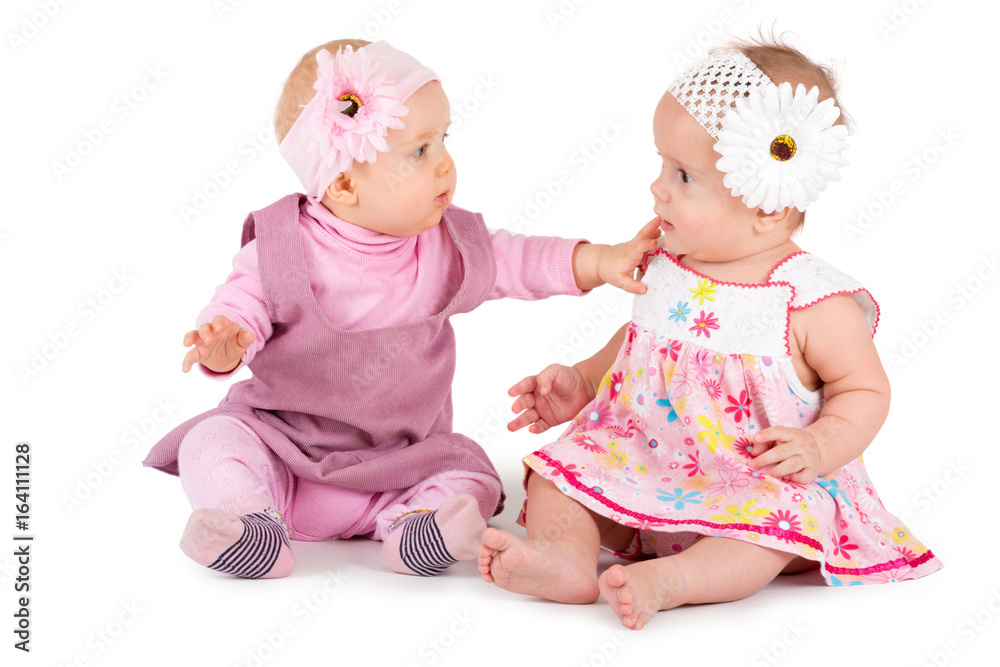 Two lovely babes in colored dresses and red hats are playing on a white background 