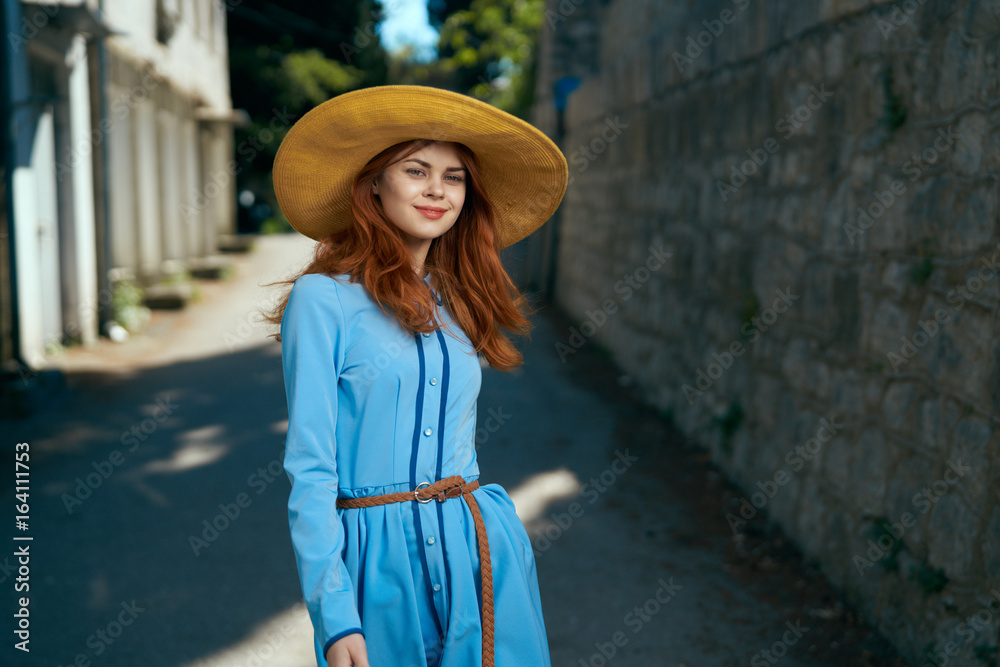 Beautiful young woman in a blue dress walking outdoors in the city