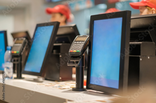 Row of order desks with computer screen and card payment terinal in fast food restaurant