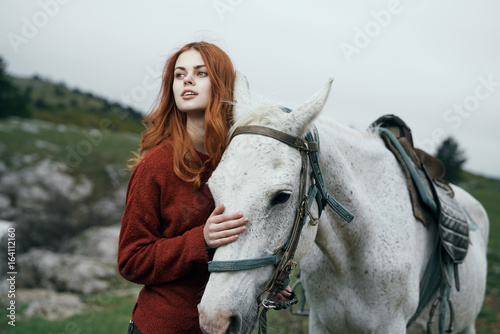 Beautiful young woman walking with her horse in the mountains