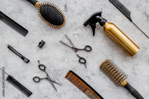 Pattern of combs and hairdresser tools on grey table background top view