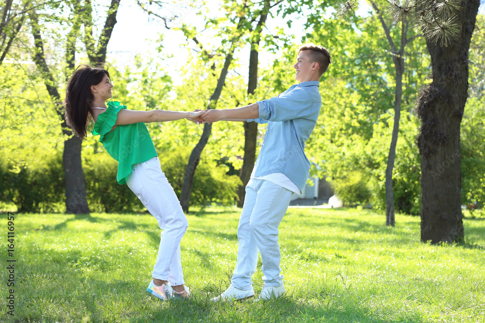Beautiful young couple dancing in park on sunny day Beautiful young couple dancing in park on sunny day