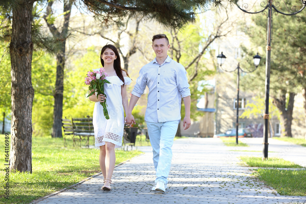 Fototapeta premium Beautiful young couple walking in park on sunny day