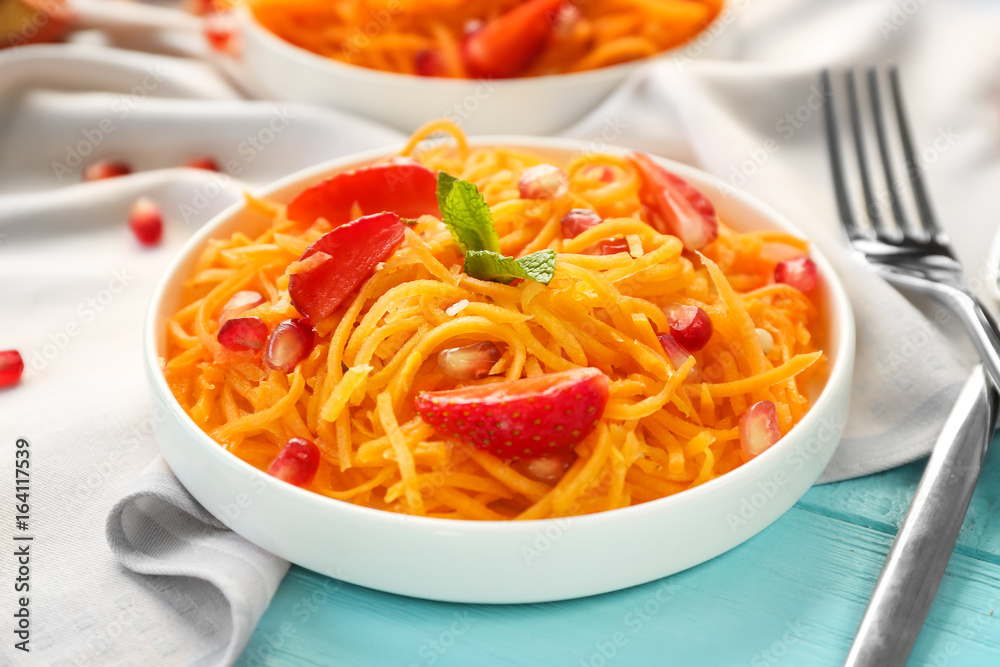 White round plate with delicious carrot strawberry salad on table, closeup