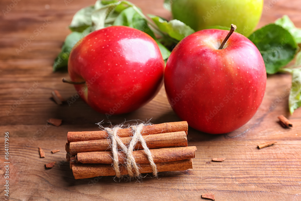 Apples with cinnamon sticks on wooden background
