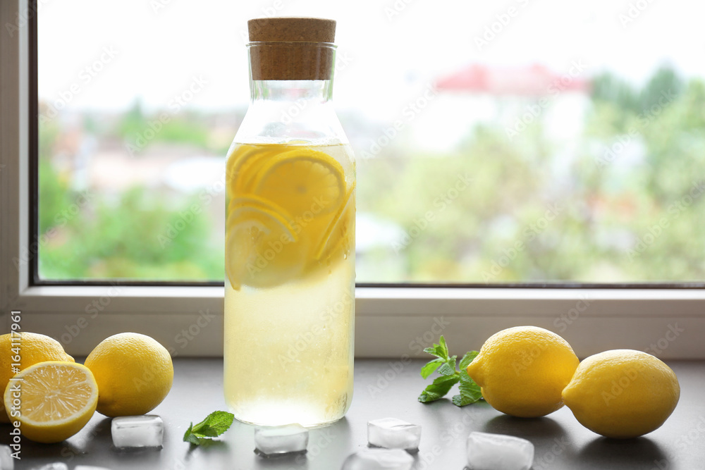 Bottle of fresh lemonade on window sill
