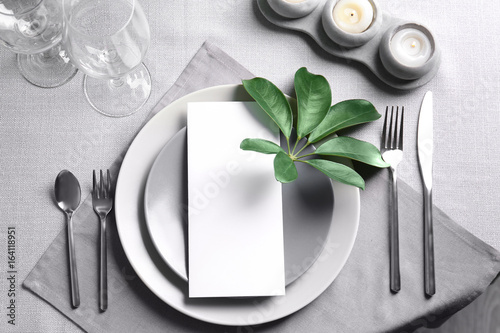 Table setting with green tropical leaves on grey  napkin
