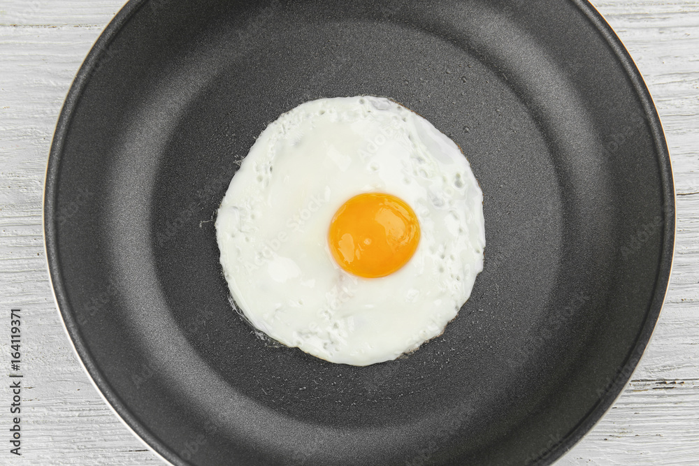 Frying pan with tasty over easy egg on wooden table Frying pan with tasty over easy egg on wooden table