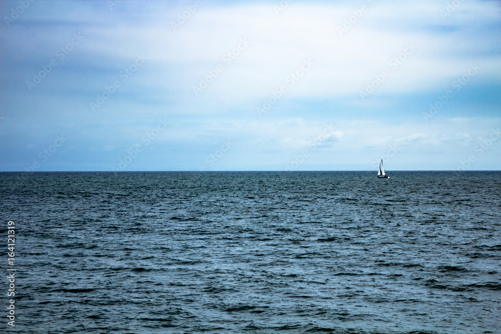 Fototapeta premium Monochromatic view of ocean with lone sailboat