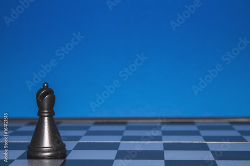 Chess as a policy. Black figure on a blue background.