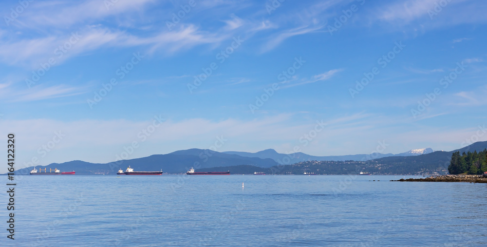 Sea landscape in summer with ships and mountains on horizon in Vancouver, Canada. Ships in the roadstead along sea coast.