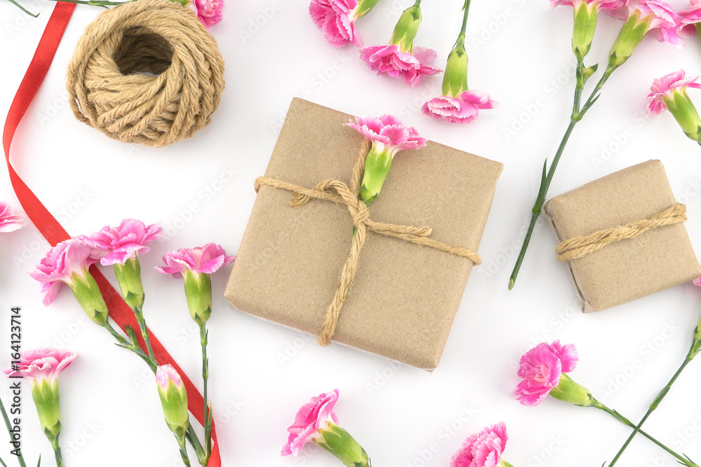 Brown gift boxes, ropes and red ribbon decorated with pink carnation flowers on white background Brown gift boxes, ropes and red ribbon decorated with pink carnation flowers on white background