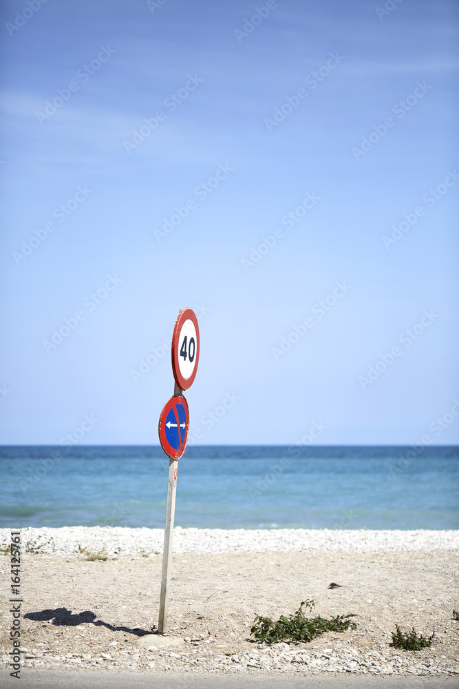 Traffic sign on a beach with horizon line and blue sky