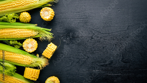 Corn. Raw Vegetables On a black wooden background. Top view. Free space for your text.
