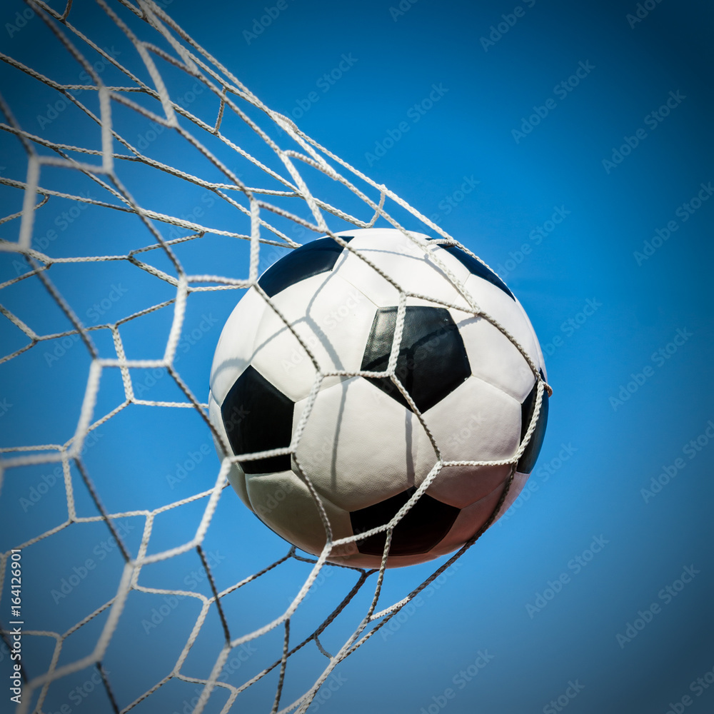 Naklejka premium Soccer football in Goal net with the sky field.
