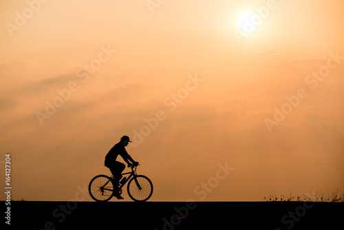 Silhouette of cyclist on sunset background