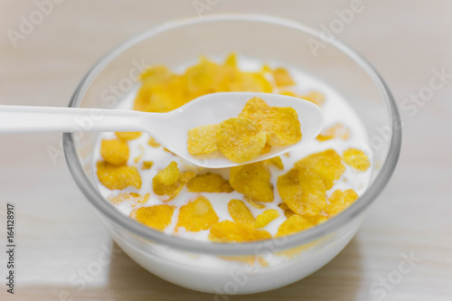 bowl of corn flakes and spoon on wood background