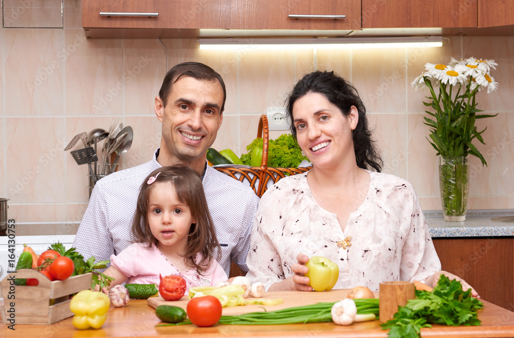 happy family with child in home kitchen interior with fresh fruits and vegetables, pregnant woman, healthy food concept