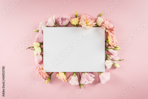 Top view of blank greeting card and tender eustoma flowers isolated on pink