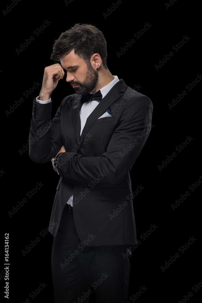 handsome bearded upset businessman in bow tie and black suit, isolated on black handsome bearded upset businessman in bow tie and black suit, isolated on black
