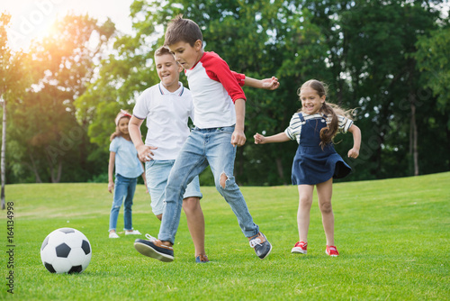 Cute happy multiethnic kids playing soccer with ball in park © LIGHTFIELD STUDIOS