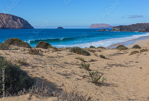 Colorful sandy seacoast of Graciosa volcanic island with black lumps of lava, Lanzarote, Canary Islands, Spain
