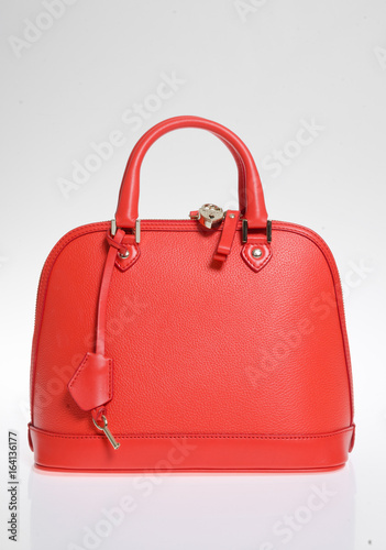 A leather designer handbag, against a white background, shot in a studio with sharp light and vivid blue and pink colours