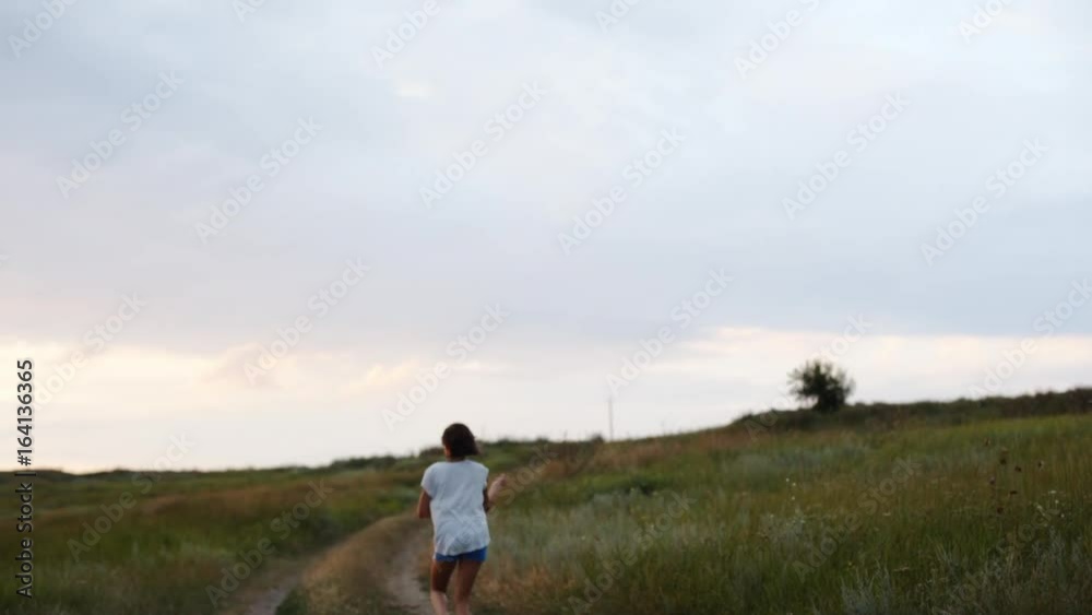 Happy little girl holding rope with kite and running on rural road in field. Happy little girl holding rope with kite and running on rural road in field.