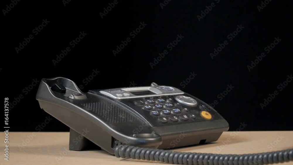 Wired phone in the office on the desk. A European man uses a telephone. Shooting in the studio on a black background. Close-up of the hands of a man. Wired phone in the office on the desk. A European man uses a telephone. Shooting in the studio on a black background. Close-up of the hands of a man.