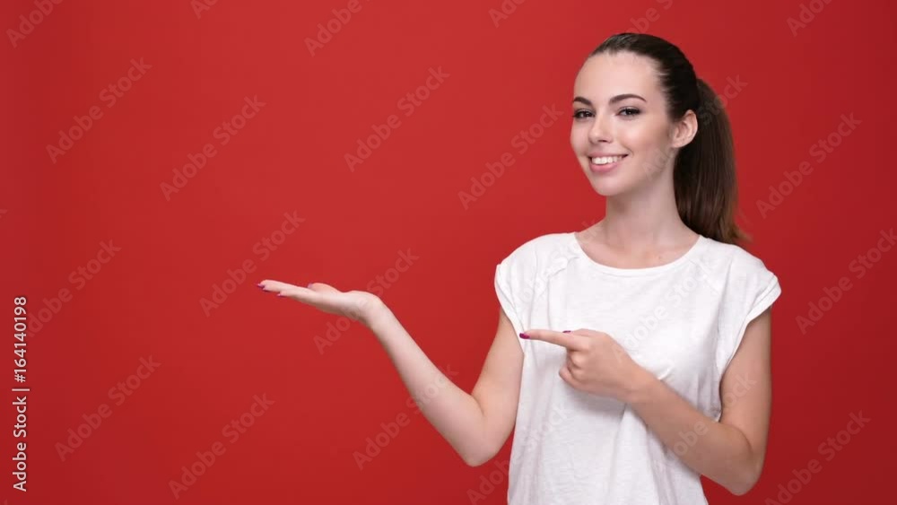 Young beautiful caucasian woman smiling and holding copyspace in hand over red background Young beautiful caucasian woman smiling and holding copyspace in hand over red background