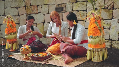 Balinese women showing caucasian woman how to make offerings photo