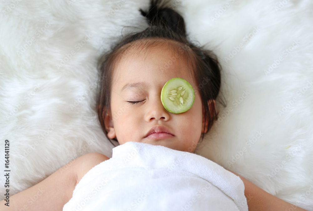 Cute little Child girl with a slice of cucumber in her eye, concept for skin care. Cute little Child girl with a slice of cucumber in her eye, concept for skin care.