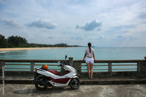 Silhouette of woman and motorbike on the hill with sea background, enjoying freedom and active lifestyle, having fun on a bikers tour