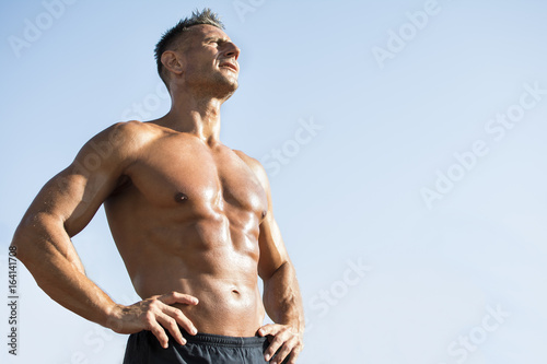 Handsome middle aged man working out on a running track. Healthy adult man sun baiting. Tanned skin and shirtless middle-aged man.