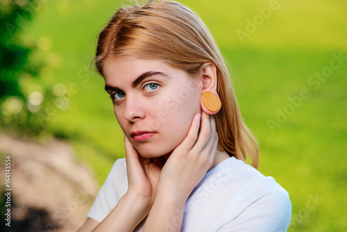 Portrait of a young beautiful woman with wooden tunnels in her ears photo