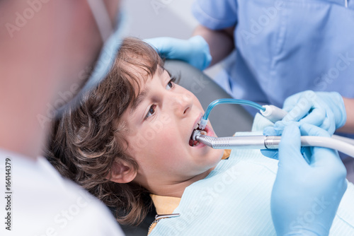 cropped shot of dentists treating teeth of boy in dental hospital