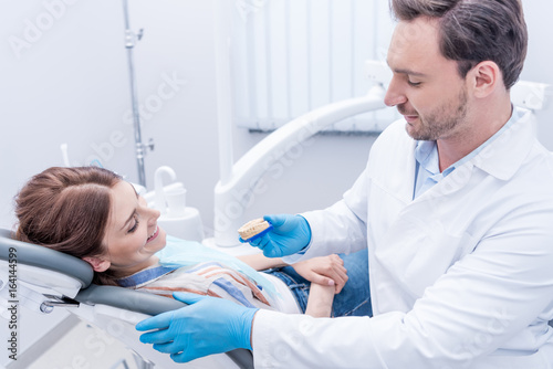 side view of dentist showing dental mold to patient in dental clinic