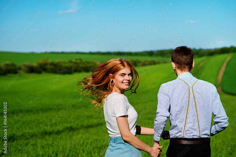Young couple running along a green field on a lovely sunny day Young couple running along a green field on a lovely sunny day