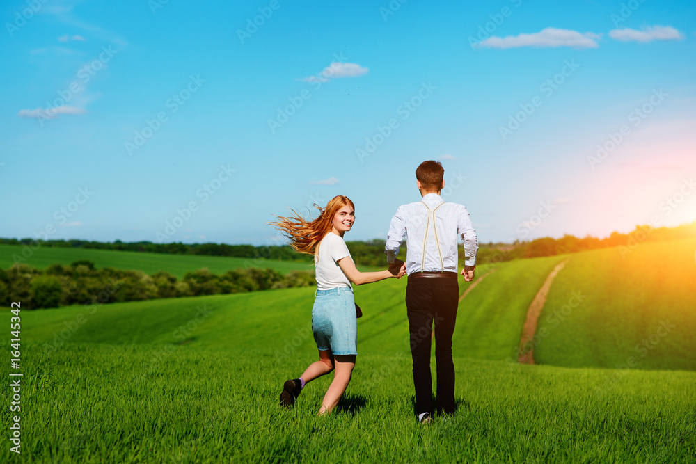 Young couple running along a green field on a lovely sunny day Young couple running along a green field on a lovely sunny day