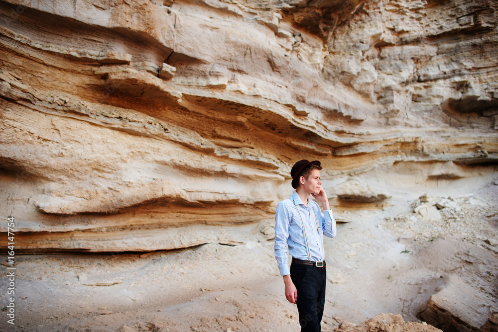 Attractive man is standing in the middle of a sand quarry and making a call from a smartphone