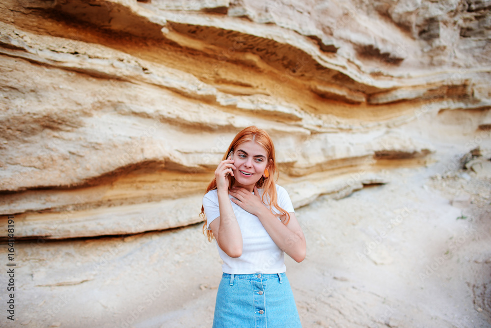 A beautiful woman is smiling and talking by smartphone on the background of a sand quarry A beautiful woman is smiling and talking by smartphone on the background of a sand quarry