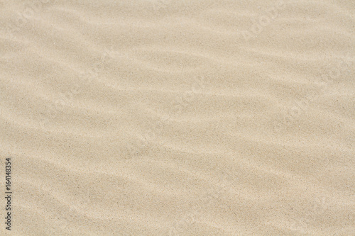 Fototapeta Naklejka Na Ścianę i Meble -  A full frame, background image of the surface of a sandy beach with soft, rippled effect sand that is light brown in colour.