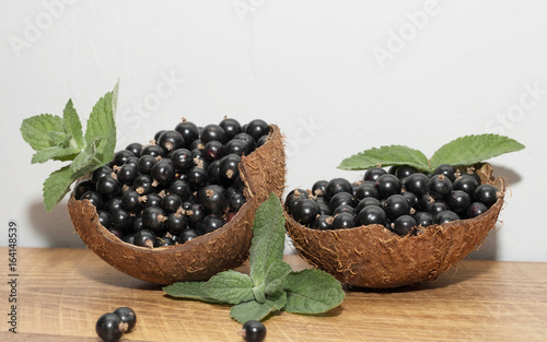  Black currant in a coconut shell with mint leaves on a texture background