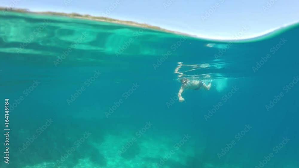 Half underwater close up, swimmer in flippers dives into the sea, raw, 4K Half underwater close up, swimmer in flippers dives into the sea, raw, 4K