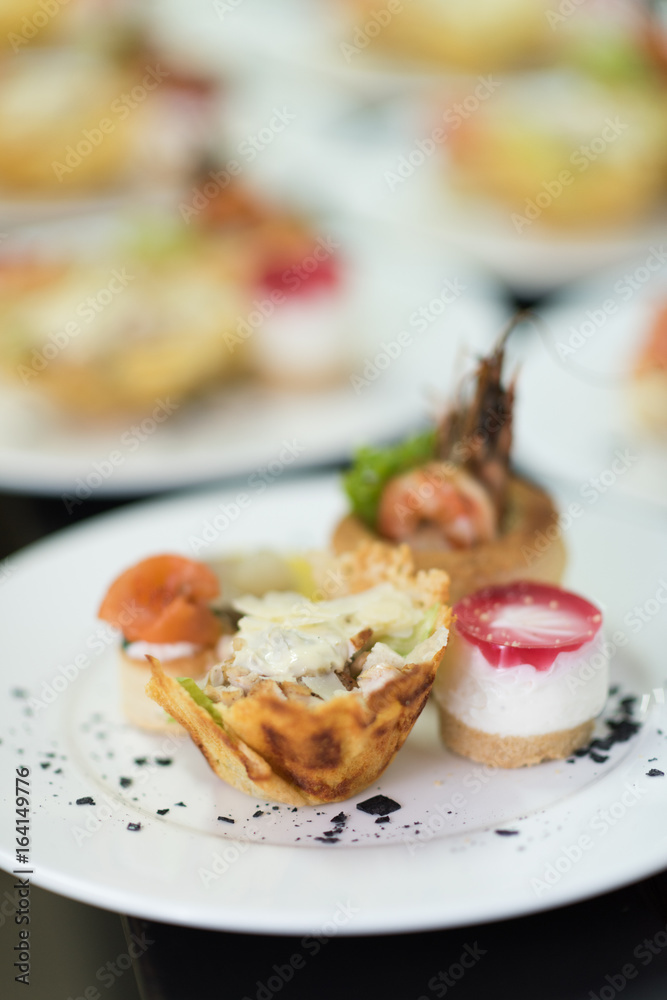 Many plates of appetizers being prepared in commercial kitchen, for an event