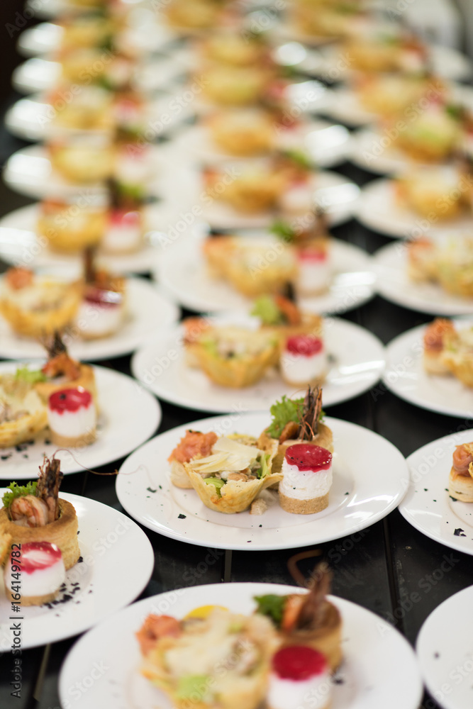 Many plates of appetizers being prepared in commercial kitchen, for an event Many plates of appetizers being prepared in commercial kitchen, for an event