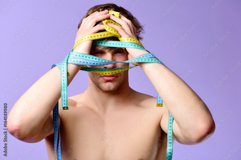 Fitness and diet concept. Guy with flexible rulers on purple - obrazy, fototapety, plakaty 