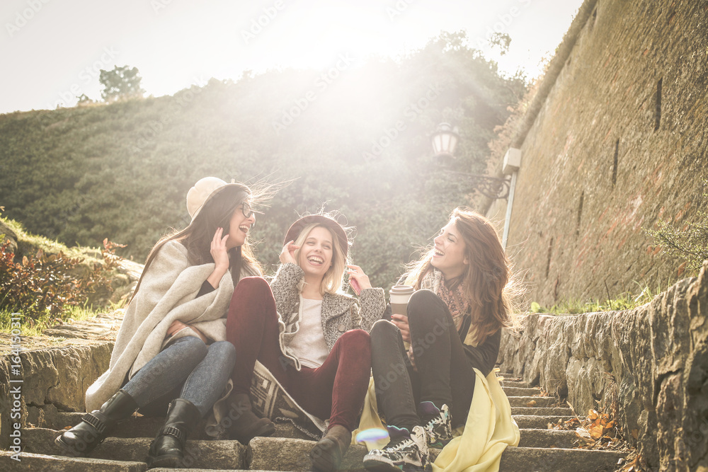 Obraz premium Three young girls sitting on the stairs at the public park. Three young girls sitting on the stairs at the public park an having conversation.