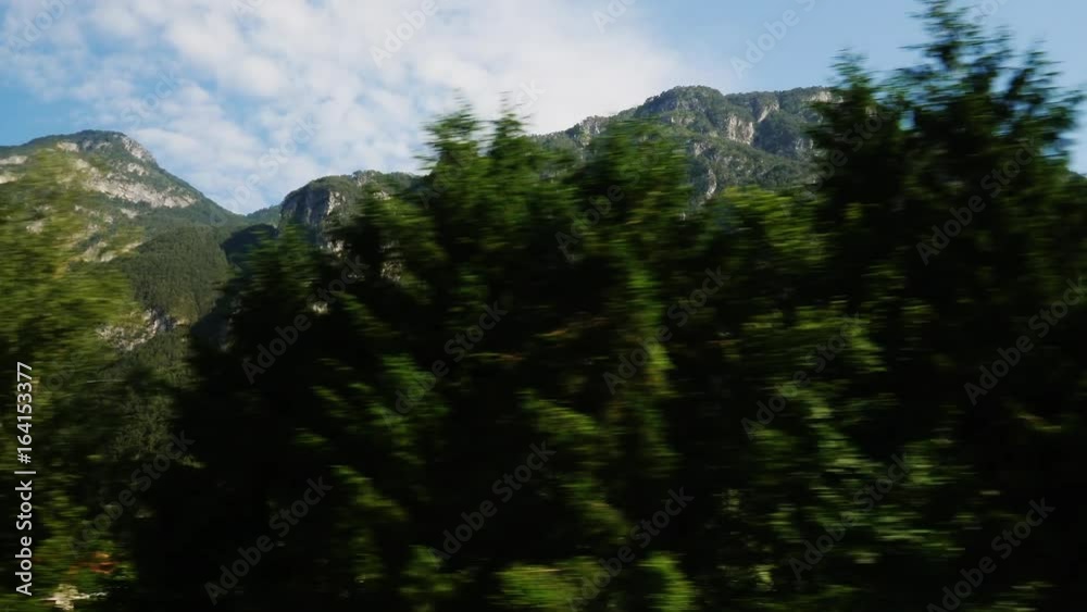 POV video: Beautiful Alps in Austria. Covered with forests, clouds can be seen above the peaks. View from the window of a moving car POV video: Beautiful Alps in Austria. Covered with forests, clouds can be seen above the peaks. View from the window of a moving car
