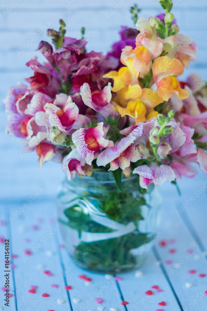 Obraz premium Still life. A bouquet of bright flowers, garden roses, in a jar of water on a light background. A romantic picture.